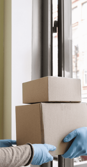 Delivery man wearing a mask and handing over the delivery to the client