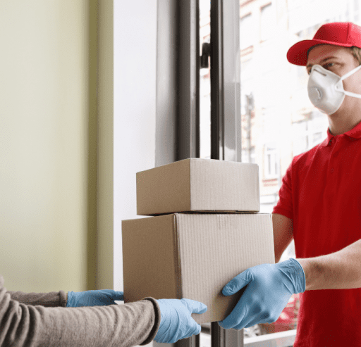 Delivery man wearing a mask and handing over the delivery to the client