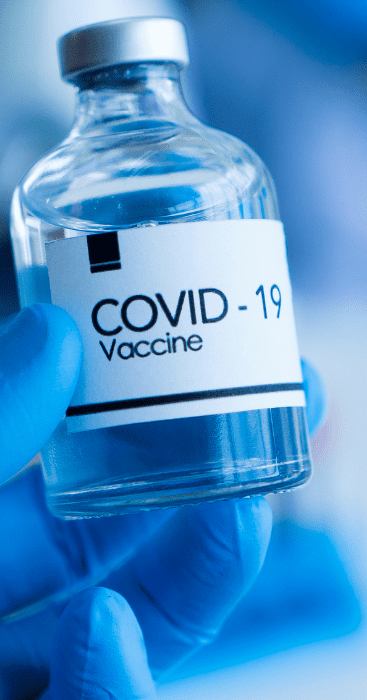 A hand in latex glove holding COVID19 vaccine bottle
