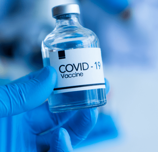 A hand in latex glove holding COVID19 vaccine bottle